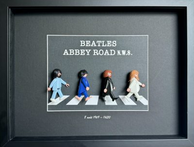Tableau Abbey Road avec quatre figurines Playmobil traversant un passage piéton sur fond gris dans un cadre noir