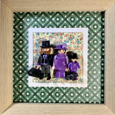 Tableau Family avec trois figurines Playmobil habillées de violet, chien noir, fond fleuri et cadre en bois clair