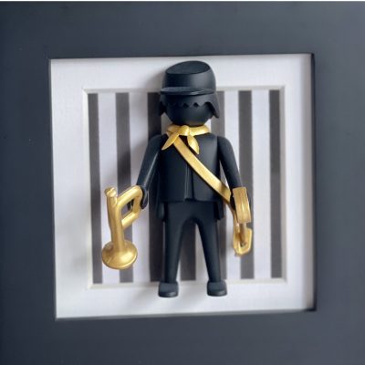 Tableau Garde à vous, figurine noire à casquette avec écharpe et clairon dorés sur fond rayé encadré de blanc