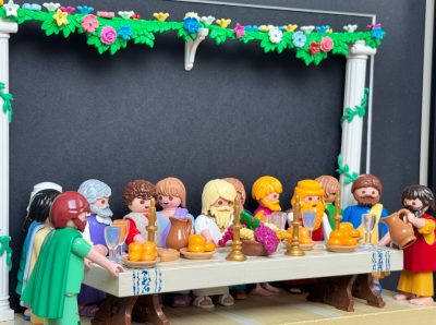 Scène de La Cène en figurines Playmobil autour d'une longue table garnie de fruits, pichets et chandeliers dorés