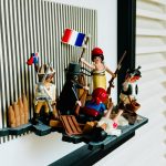 Détail de La Liberté guidant le peuple, figurines Playmobil en relief avec drapeau tricolore et fusils dans un cadre noir