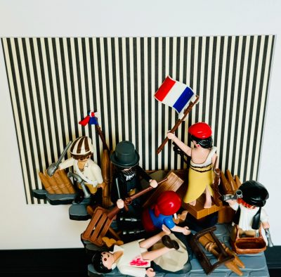Scène Playmobil de La Liberté guidant le peuple, figurine brandissant un drapeau tricolore sur une barricade rayée