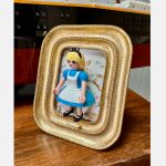 Tableau ALICE, figurine Playmobil en robe bleue et tablier blanc dans un cadre doré à perles sur fond fleuri