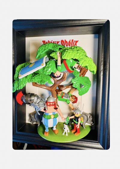 Tableau Astérix et Obélix, figurines Playmobil sous un arbre avec Idéfix, sangliers et Romains, cadre noir