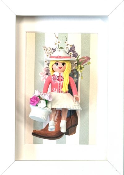 Tableau Cowgirl : figurine Playmobil blonde en robe rose, chapeau fleuri et panier de roses, devant une botte de cowboy