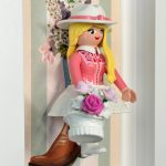 Figurine Playmobil blonde au chapeau blanc et corsage rose tenant un panier de roses, tableau Cowgirl