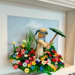 Tableau La Femme à l'ombrelle, figurine Playmobil coiffée d'un canotier tenant une ombrelle verte au milieu d'un massif de