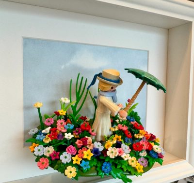 Tableau La Femme à l'ombrelle, figurine Playmobil coiffée d'un canotier tenant une ombrelle verte au milieu d'un massif de