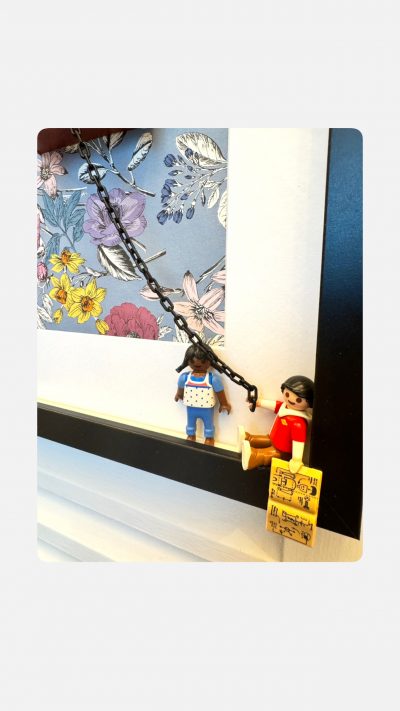 Détail du tableau J'AI RÊVÉ : deux figurines Playmobil sur une balançoire à chaîne devant un fond floral bleu encadré