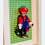 Tableau Super MARIO, figurine Playmobil en salopette bleue et casquette rouge sur fond vichy vert dans un cadre blanc