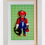 Figurine Playmobil Super MARIO en casquette rouge et salopette bleue sur fond vichy vert, dans un cadre blanc