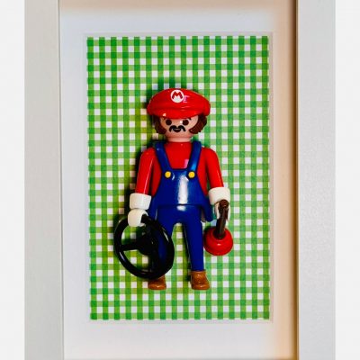 Figurine Playmobil Super MARIO en casquette rouge et salopette bleue sur fond vichy vert, dans un cadre blanc