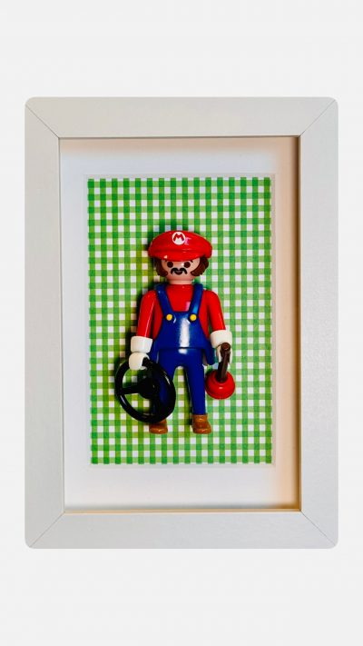 Figurine Playmobil Super MARIO en casquette rouge et salopette bleue sur fond vichy vert, dans un cadre blanc
