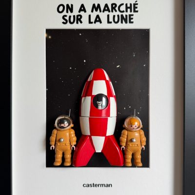 Tableau TINTIN de Mlle Louise, fusée rouge et blanche et deux figurines en scaphandre orange sur fond étoilé