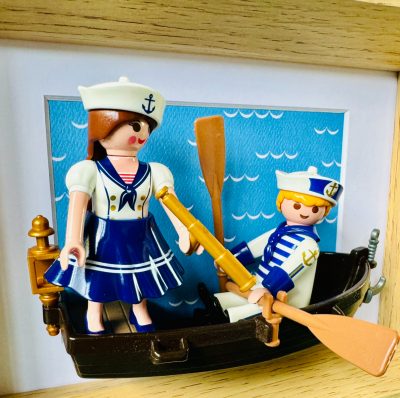 Detail du tableau Toi, moi et l'Atlantique, deux figurines en tenue de marin dans une barque sur fond de vagues