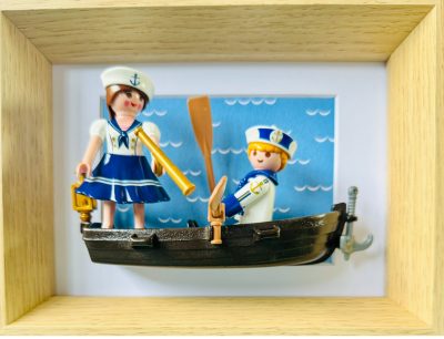 Tableau Toi, moi et l'Atlantique avec deux figurines Playmobil en tenue de marin dans une barque noire, cadre en bois clair