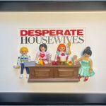 Quatre figurines miniatures représentées autour d’un comptoir, avec des accessoires de cuisine et des verres, sur un fond blanc portant le titre "Desperate Housewives".