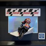 Figurine miniature de pilote de moto en combinaison rouge et noire sur une moto noire portant le numéro 20, dans un cadre noir avec un panneau "GP MotoGP moto" et une plaque "World Champion 2021"