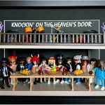 Treize figurines miniatures représentant des musiciens et personnages variés, réunies autour d’une longue table garnie de plats, avec des instruments et enceintes en haut, sous un panneau "Knockin' on the Heaven's Door".