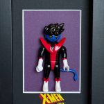 Figurine miniature bleue avec cheveux noirs en piques, portant un costume noir, rouge et blanc, avec une queue bleue, encadrée sur un fond violet avec le logo "X-Men '97" en dessous.