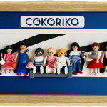 Dix figurines miniatures représentant divers personnages devant une boulangerie-pâtisserie, avec des pains et des viennoiseries, dans un cadre bleu et bois clair avec le logo "Cokoriko" et les mentions "artisan boulanger pâtissier".