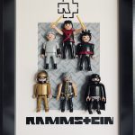 Six figurines miniatures représentant les membres du groupe Rammstein, habillées en costumes noirs, gris et or, avec accessoires caractéristiques, posées sur un fond gris à motifs dans un cadre noir avec le logo et le nom du groupe en bas.