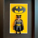 Tableau BATMAN avec figurine Playmobil en costume gris et cape noire devant le logo chauve-souris sur fond jaune