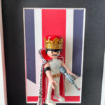 Figurine Playmobil Freddie Mercury avec couronne dorée, cape rouge et micro devant un drapeau britannique
