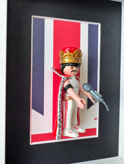Tableau FREDDIE MERCURY, figurine Playmobil couronne doree, cape et micro devant un drapeau britannique
