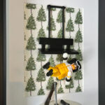 Figurine Playmobil en combinaison jaune suspendue sous un télésiège noir devant un fond de sapins peints, skis dans la neige