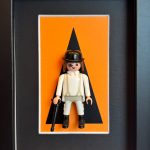 Tableau Orange Mécanique, figurine Playmobil en tenue blanche, chapeau melon, canne et cil peint sur fond orange