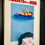 Tableau Les Dents de la mer avec figurine Playmobil surfeuse sur planche bleue et requin gueule ouverte sous elle