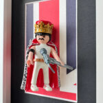 Tableau Freddie Mercury, figurine Playmobil couronnée et cape rouge devant un drapeau britannique, vue en angle