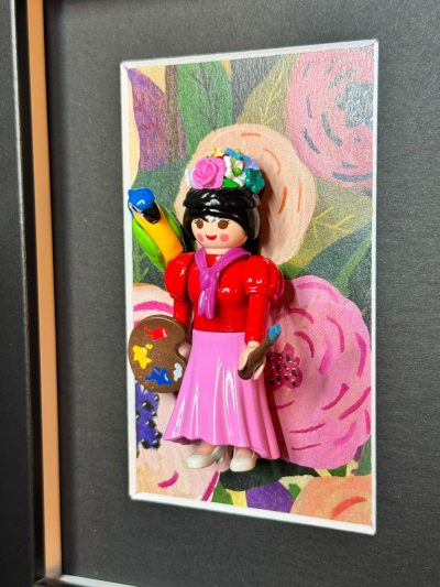 Figurine Playmobil Frida Kahlo en jupe rose avec palette, pinceau, perroquet et couronne de fleurs sur fond floral
