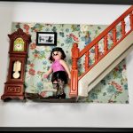 Figurine Playmobil moustachue en haut rose et jupe noire portant un aspirateur près d'un escalier orange, tableau I want to