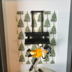 Figurine Playmobil skieur en combinaison jaune et blanche suspendue sous un télésiège noir, fond à motifs de sapins