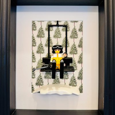 Tableau JEAN CLAUDE DUSSE, figurine Playmobil en combinaison jaune bloquée sur un télésiège devant un fond de sapins