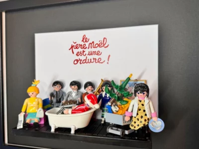 Tableau Le Père Noël est une ordure avec figurines Playmobil, titre manuscrit rouge et personnage en costume rouge dans une
