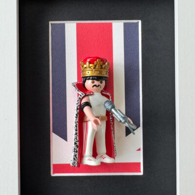 Tableau Freddie Mercury avec figurine Playmobil couronnee et cape sur fond Union Jack, cadre blanc