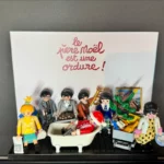 Tableau Playmobil Le Père Noël est une ordure avec titre manuscrit rouge, personnages et Père Noël dans une baignoire