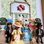 Detail du tableau Bridgerton, figurines Playmobil en robes et hauts-de-forme devant un decor floral vert d'eau
