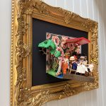 Tableau Le déjeuner des canotiers avec figurines Playmobil attablées sous un store rouge, cadre doré sculpté