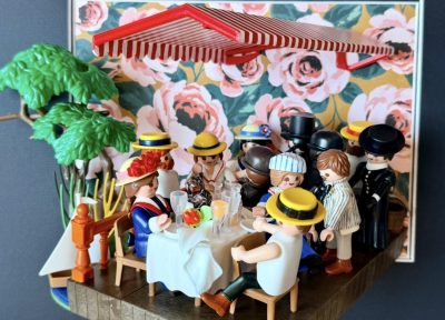 Scène du Déjeuner des canotiers recréée en figurines Playmobil sous un store rayé rouge, table dressée et fond fleuri