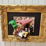 Tableau Le déjeuner des canotiers en figurines Playmobil sous un store rayé rouge et blanc, cadre doré ouvragé
