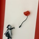 Détail de la main tendue, des touches blanches sur la figurine noire et du ballon cœur rouge.