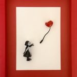 Vue de face du tableau : petite fille noire et ballon cœur rouge dans un cadre rouge.