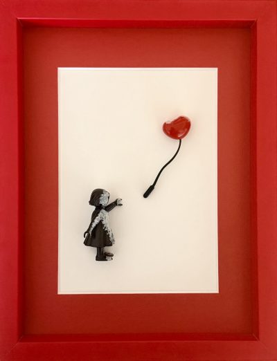 Vue de face du tableau : petite fille noire et ballon cœur rouge dans un cadre rouge.