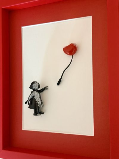 Vue de trois quarts montrant le relief de la petite fille et du ballon cœur rouge.