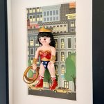 Wonder Woman vue en oblique, un bras avancé, avec tiare dorée, cheveux noirs et bottes rouges bordées de blanc.