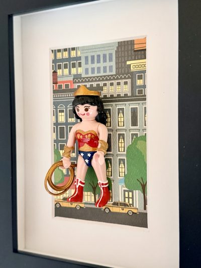 Wonder Woman vue en oblique, un bras avancé, avec tiare dorée, cheveux noirs et bottes rouges bordées de blanc.